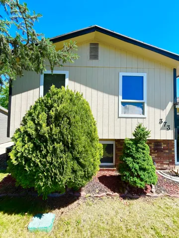 Exterior featuring vertical siding, a dark roofline, and brick foundation accents
