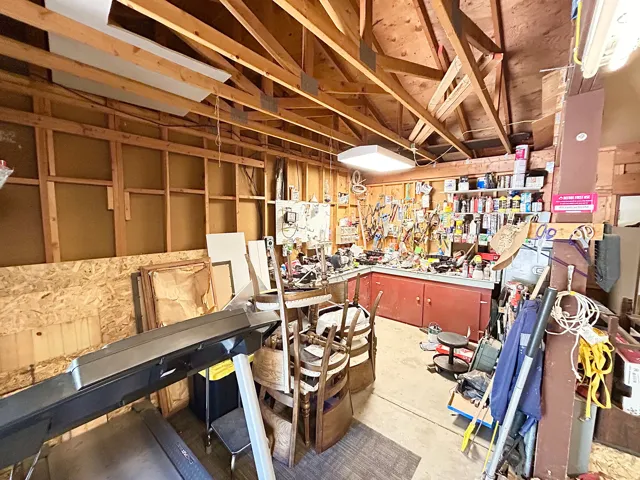 Garage space featuring exposed wood framing and a high ceiling