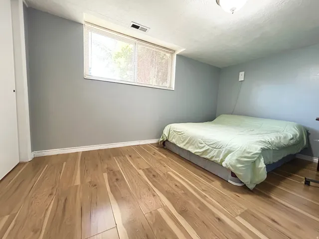Light wood-finish flooring complements the neutral wall color in this room featuring a window with blinds and white trim