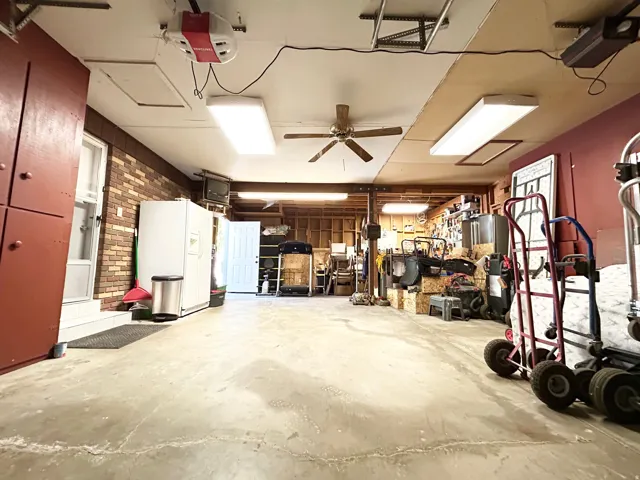 Spacious garage featuring a concrete floor, exposed ceiling beams, and overhead track lighting