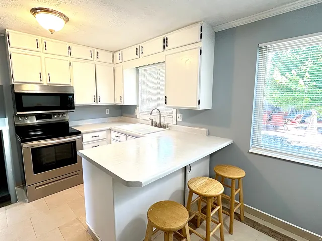 Kitchen featuring white cabinetry, stainless steel appliances, a bar-height counter, and tiled flooring