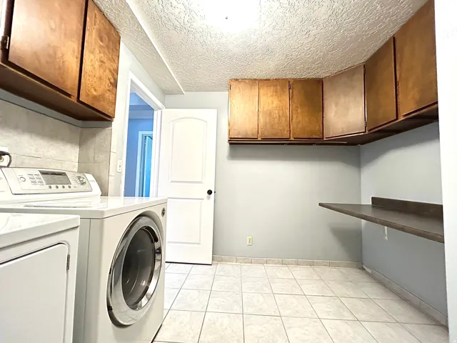 Practical utility space featuring ample wood cabinetry, a tiled floor, and a built-in folding counter
