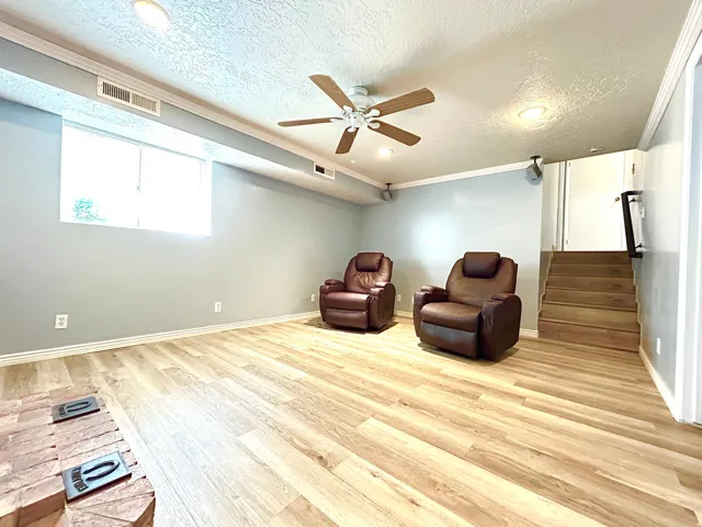 Spacious room featuring wood-finish flooring, a ceiling fan with integrated lighting, recessed lighting, and a window providing natural illumination