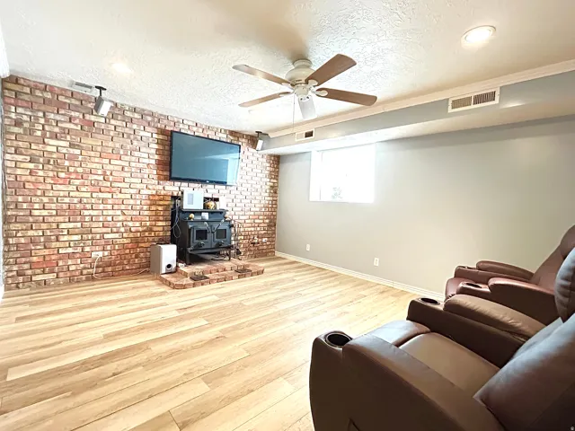Spacious room featuring a prominent brick accent wall with a built-in hearth and dark finish appliance
