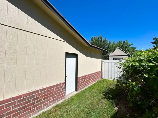 Exterior siding featuring a light tan finish over a red brick foundation