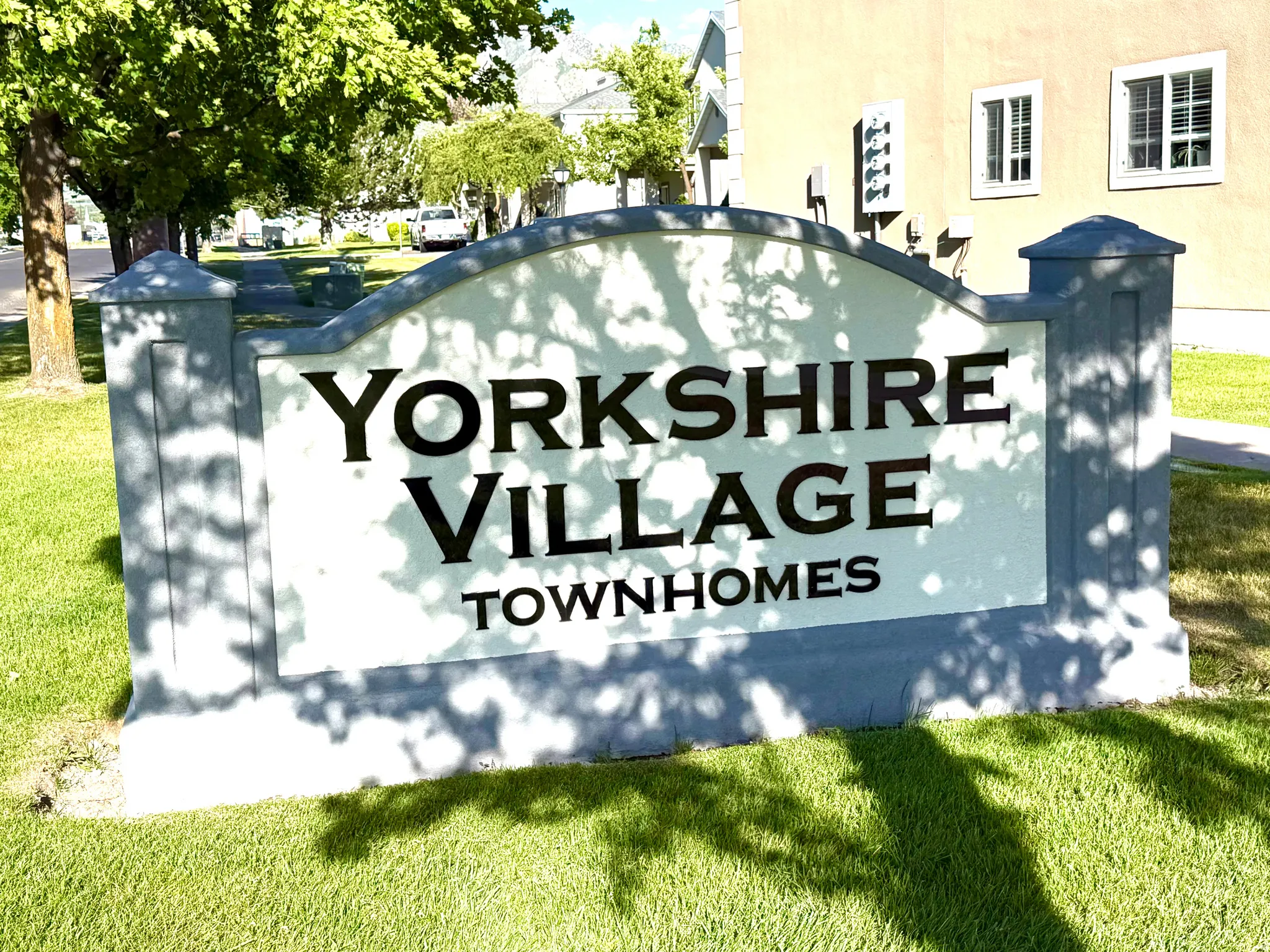 Yorkshire Village Townhomes entrance sign featuring a manicured lawn and mature trees