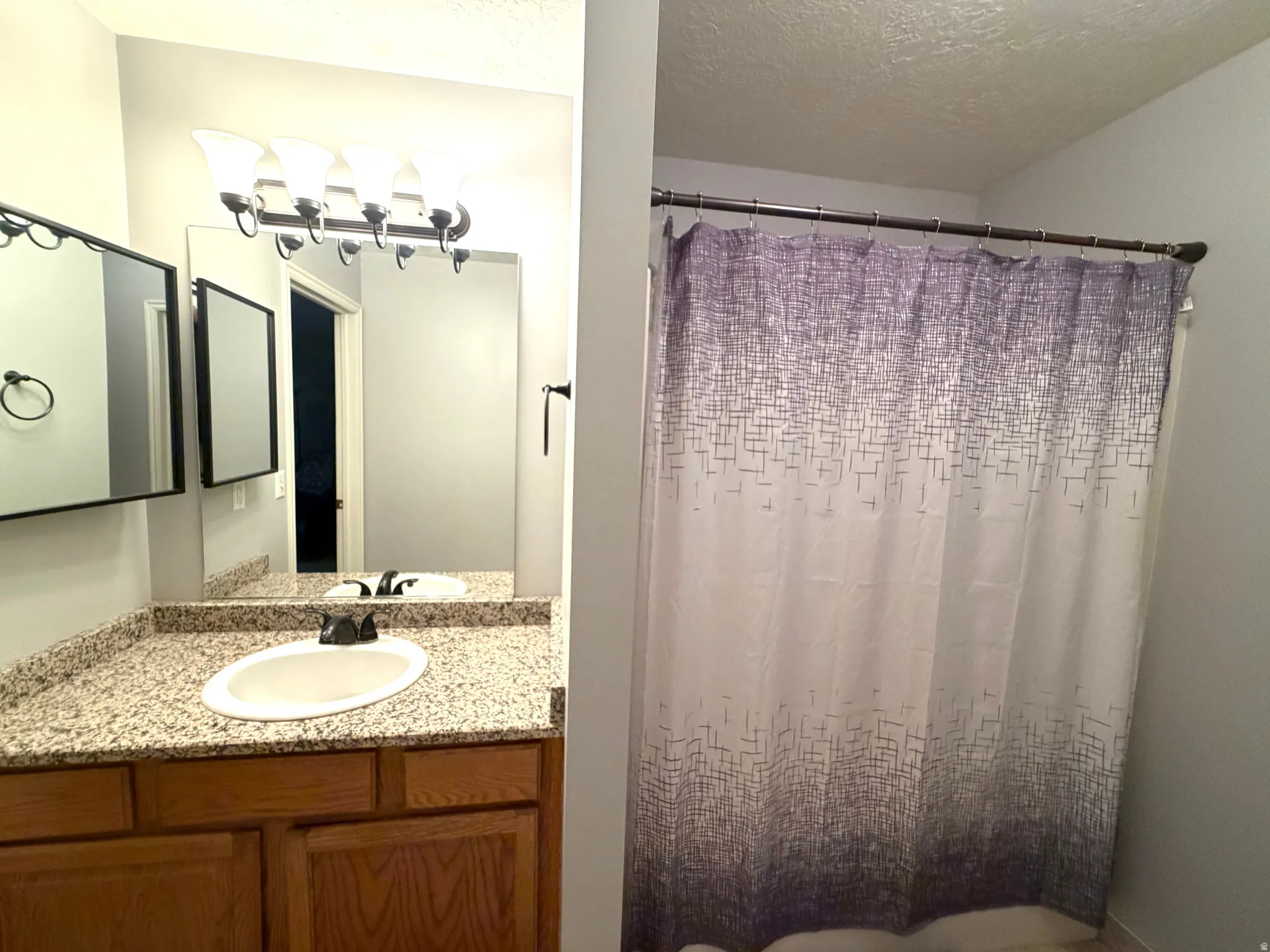 Bathroom vanity with a granite-style countertop, undermount sink, and dark bronze faucet