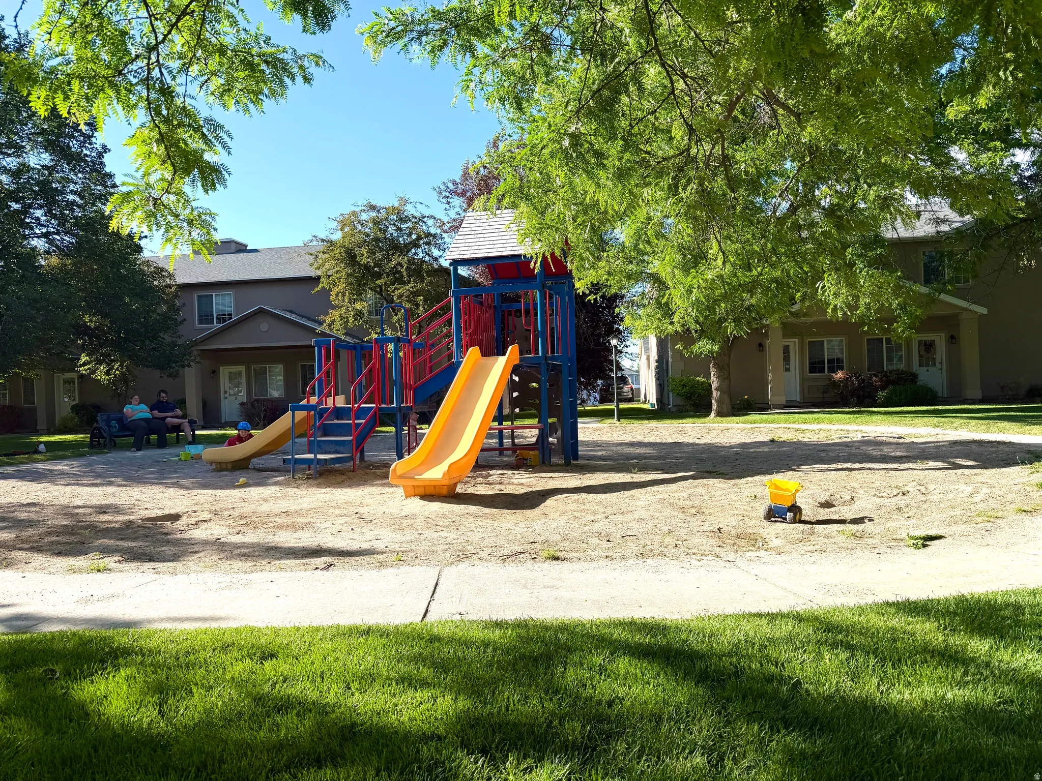 Central playground featuring multiple slides and climbing structures on a sand base