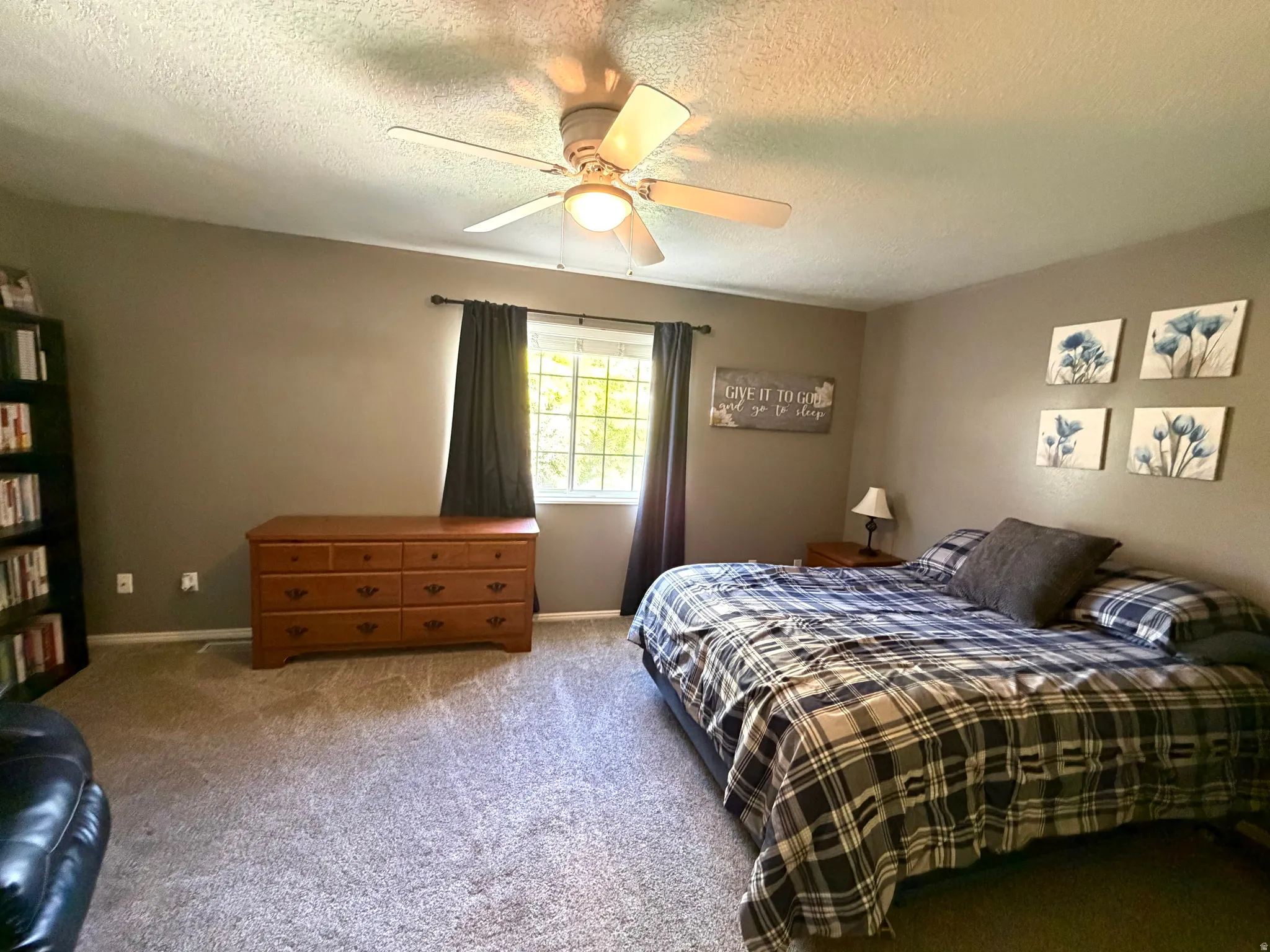 Carpeted bedroom featuring a ceiling fan with integrated lighting, a window with dark draperies, and neutral wall tones