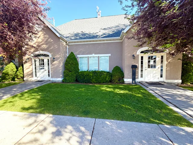 Stucco exterior with arched entryways, white double doors, and a grey shingle roof