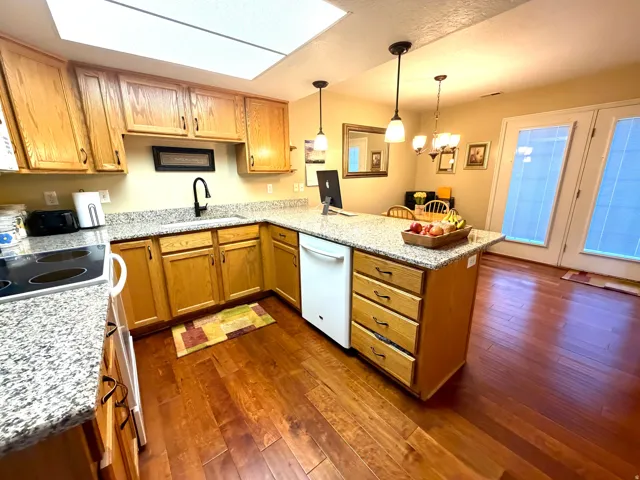 Kitchen featuring wood-finish flooring, granite countertops, and light wood cabinetry with dark hardware