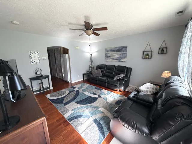 Living area featuring wood-finish flooring, a ceiling fan, and light gray wall paint