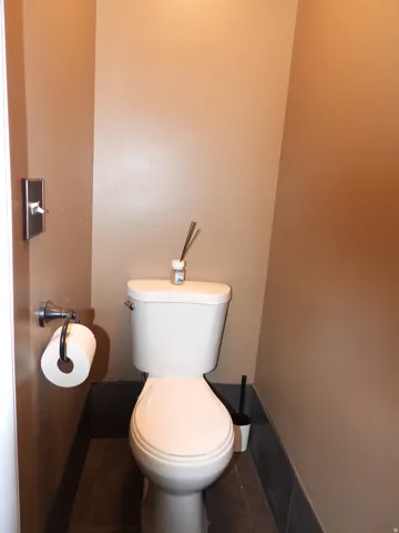 White toilet with chrome flush lever, set against neutral-toned walls