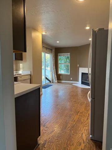 Recessed lighting, wood-finish flooring, sliding glass door, kitchen cabinetry, and built-in fireplace