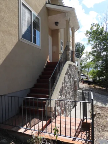 Stucco exterior featuring a covered entry porch with stone accents