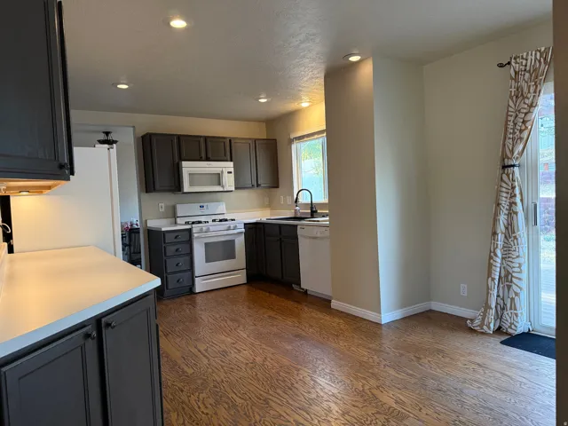 Kitchen featuring dark cabinetry, light countertops, wood-finish flooring, recessed lighting, and a sliding glass door