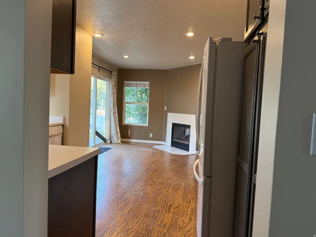 Open-concept living area featuring wood-finish flooring, recessed lighting, and a white tile fireplace surround