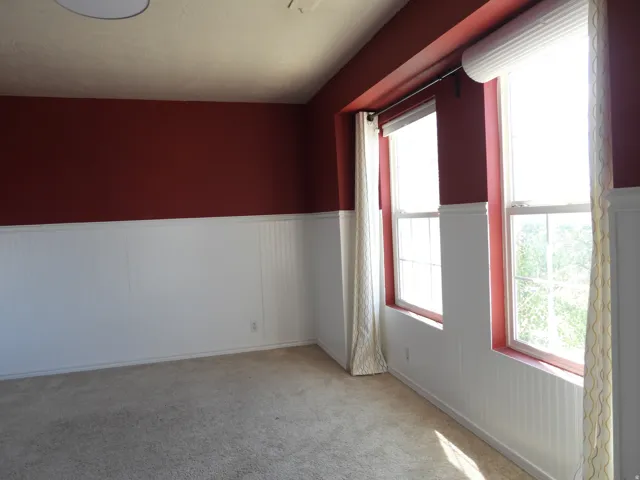 Room featuring two windows, carpeted flooring, and a flat ceiling