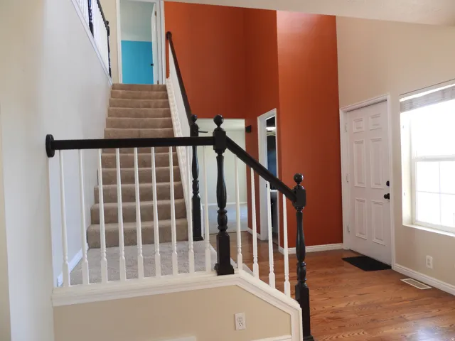 Carpeted staircase with white balusters and dark newel posts