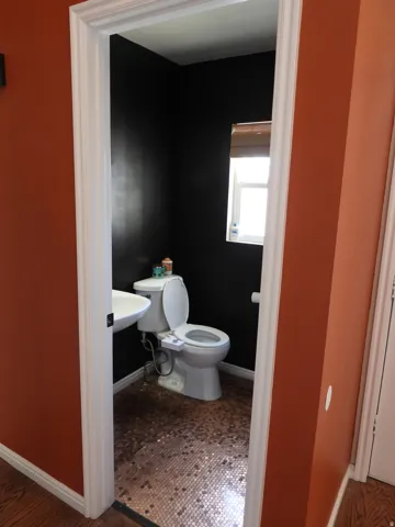 Compact powder room featuring a wall-mounted sink, a toilet, a small window, and mosaic tile flooring