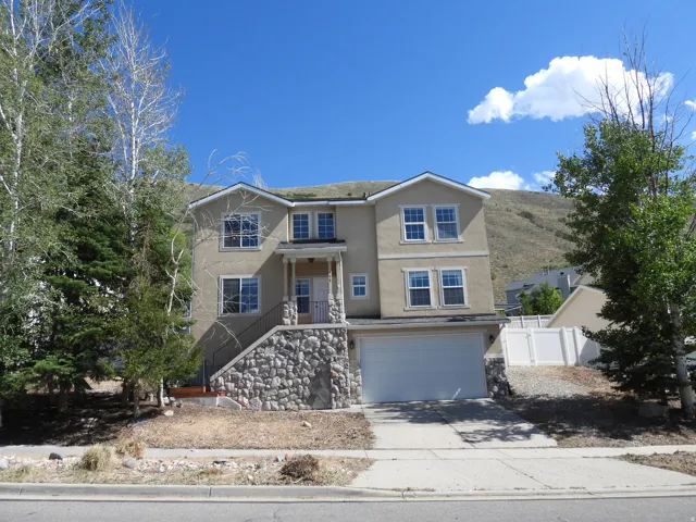 Two-story stucco residence featuring a stone-clad foundation, covered front entry, and an integrated two-car garage