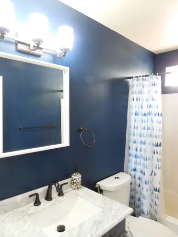 Bathroom vanity featuring a white rectangular sink, a stone-finish countertop, and a dark-finish faucet