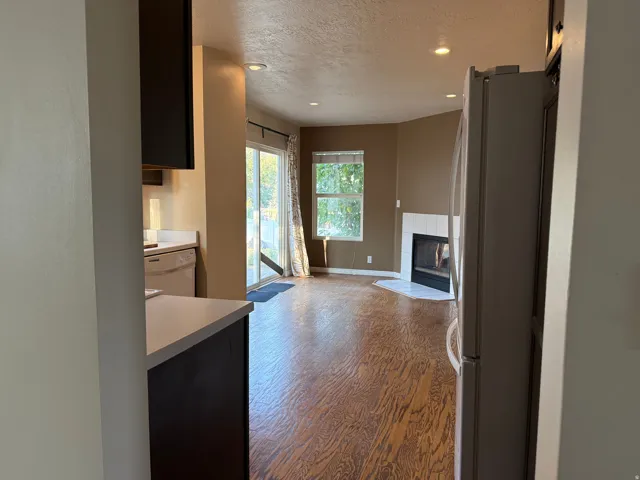Recessed lighting, wood-finish flooring, white tile fireplace surround, sliding glass door, and a window for natural light