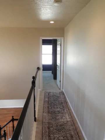 Upper-level hallway featuring a textured ceiling, recessed lighting, and a white smoke detector