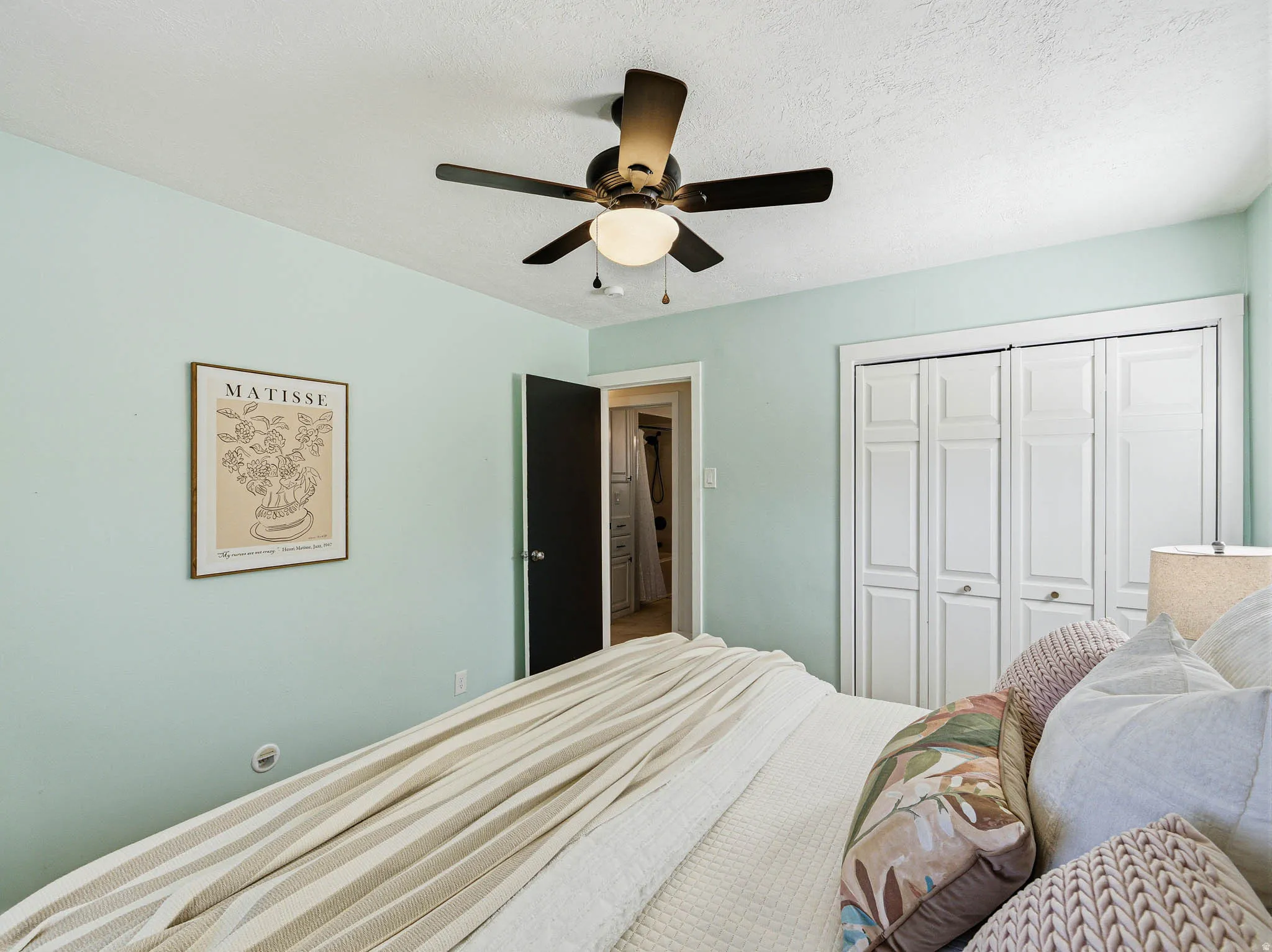 Interior space featuring a ceiling fan with integrated lighting, a dark-paneled door, and white bi-fold closet doors