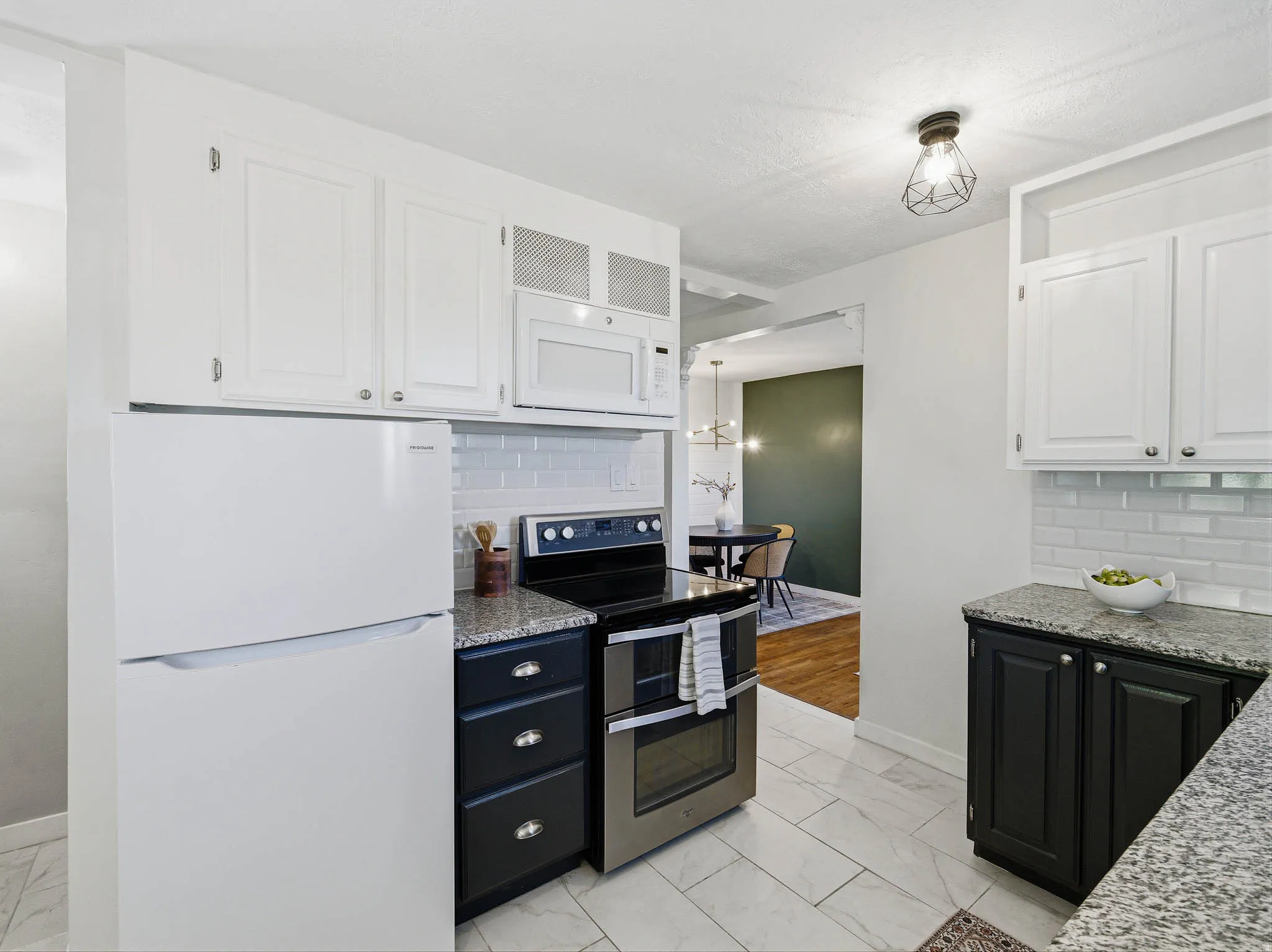 Kitchen featuring white upper cabinetry, dark lower cabinetry, granite-style countertops, subway tile backsplash, and tile flooring