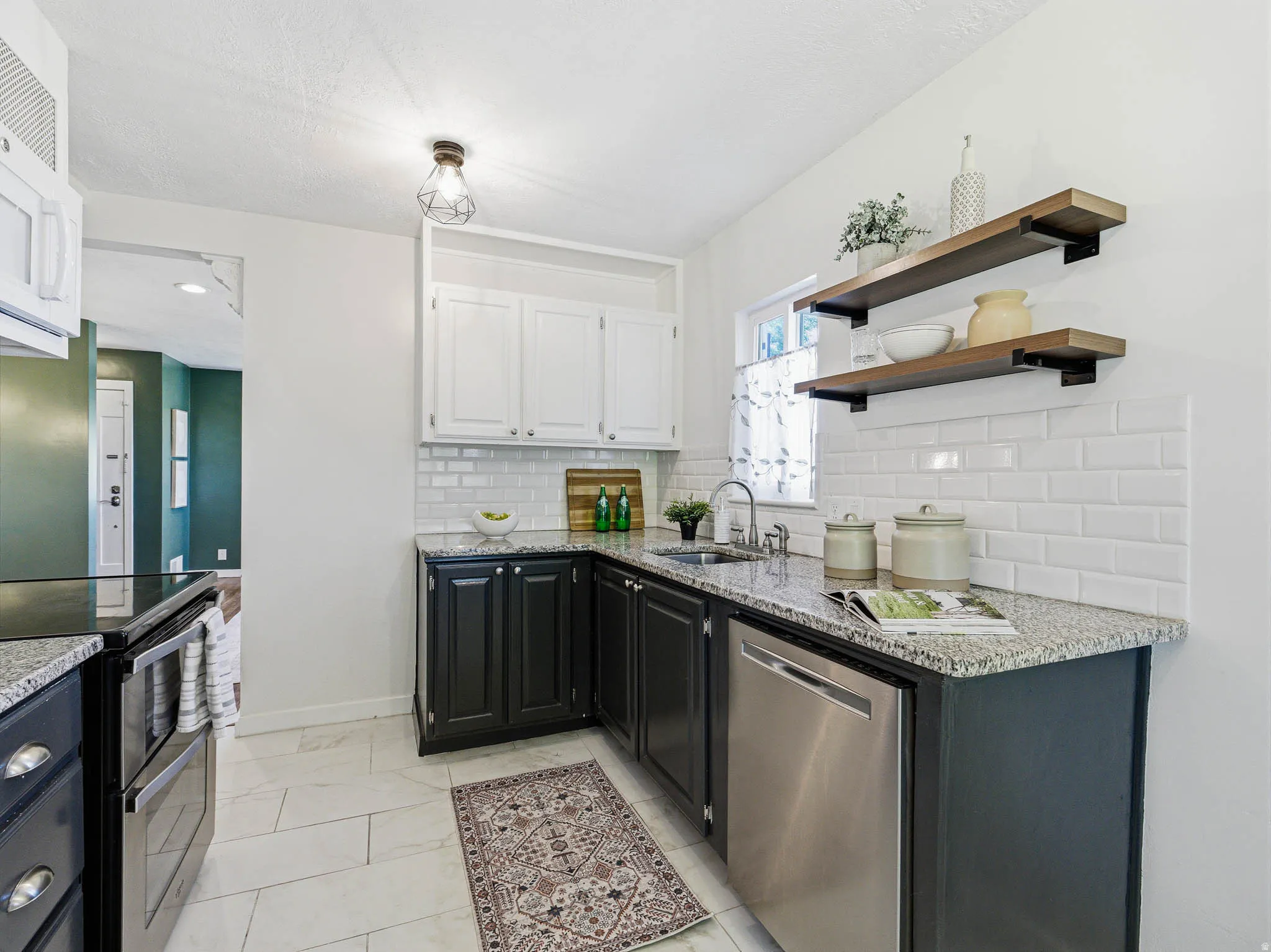 Kitchen featuring granite countertops, stainless steel dishwasher, white subway tile backsplash, wood-finish open shelving, and recessed lighting