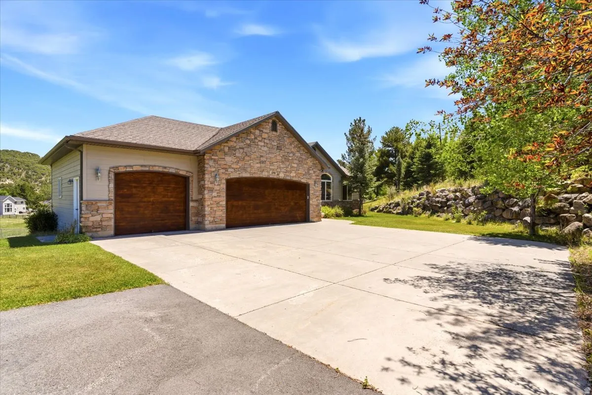 Attached two-car garage featuring arch-top wood-finish doors and stone veneer accents