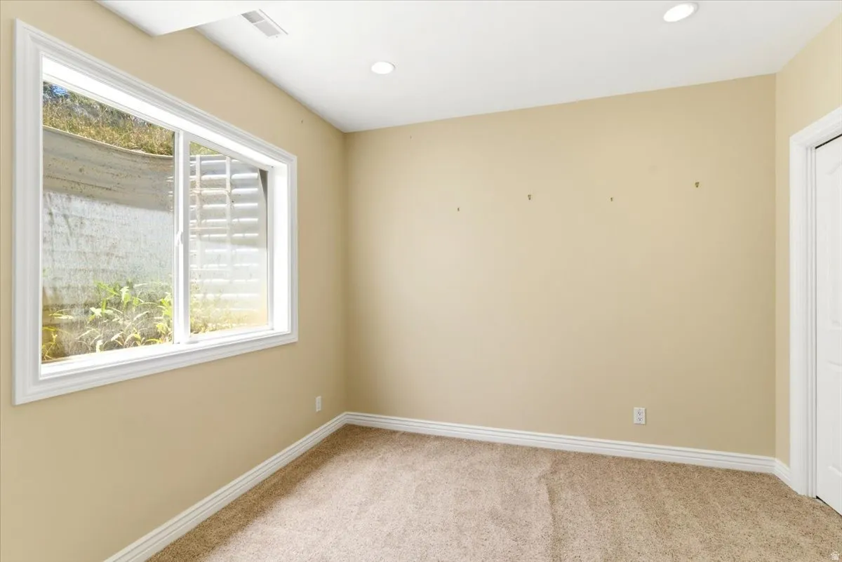 Recessed lighting illuminates this room, featuring light-toned carpeting and a white trim package
