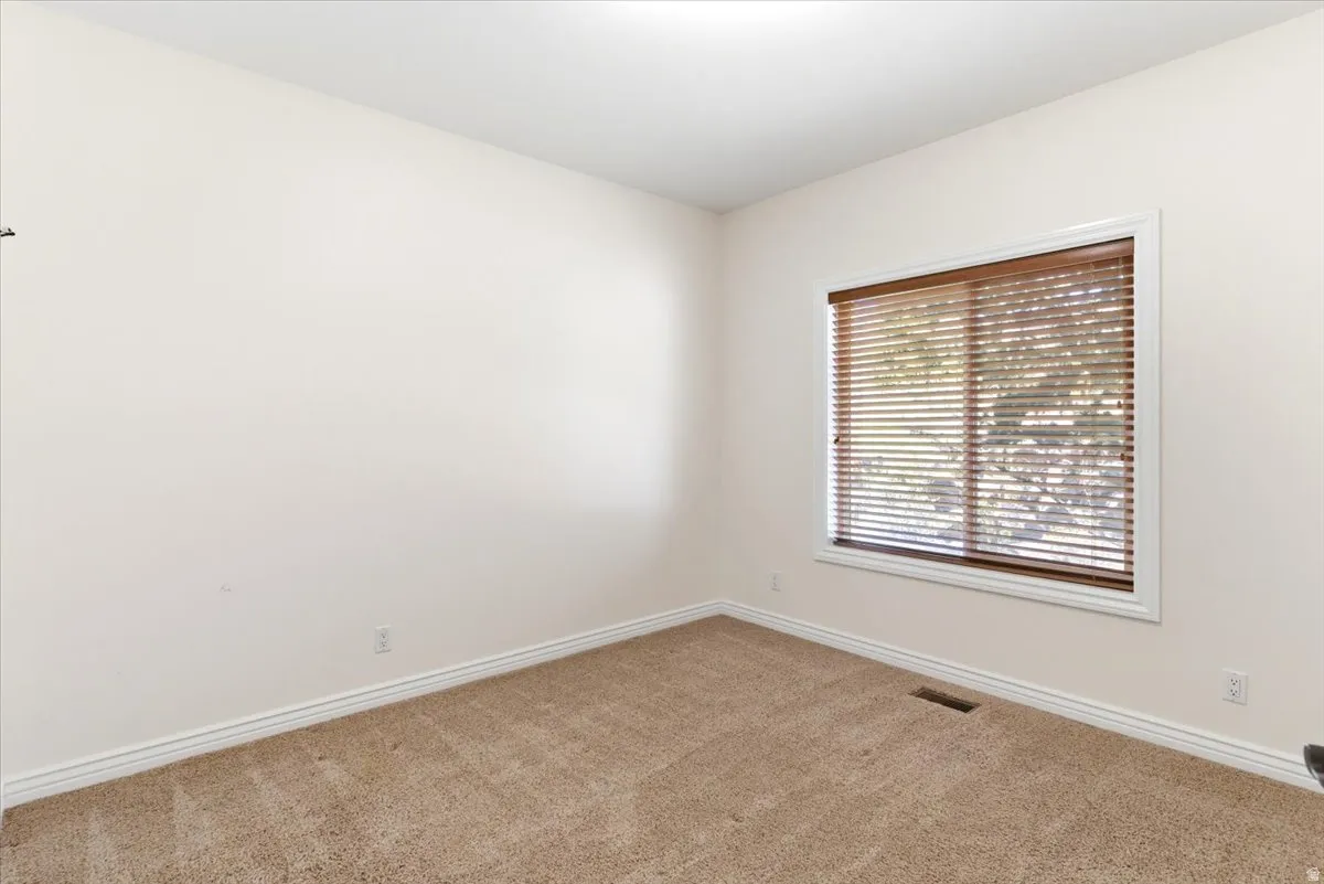 Room featuring light beige carpet flooring and white baseboards
