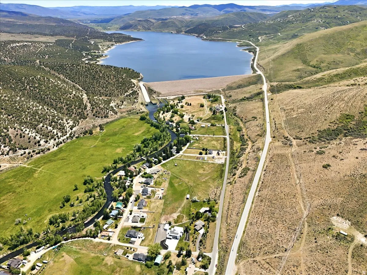 Aerial perspective showcasing a large body of water, extensive green fields, and surrounding mountainous terrain