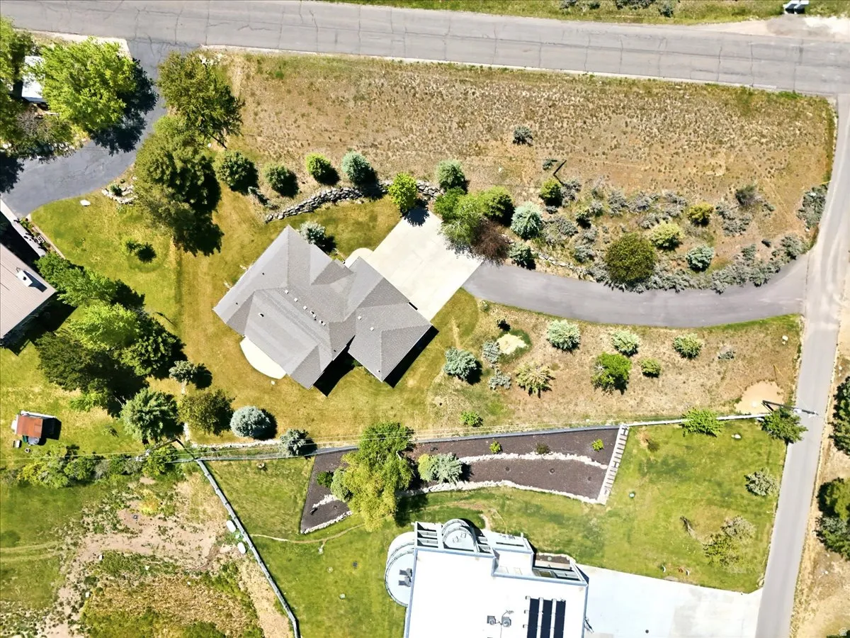 Aerial perspective highlighting the property with an asphalt driveway and mature landscaping