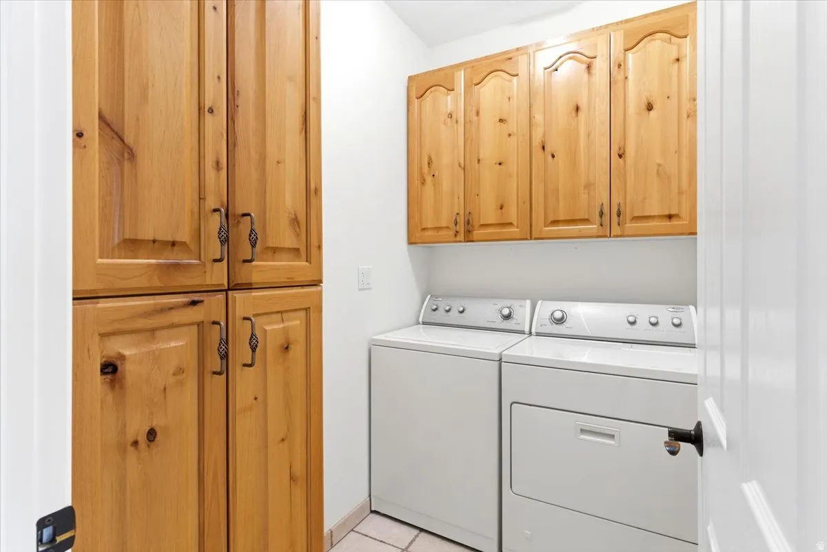 Laundry area featuring light wood-finish cabinetry, tile flooring, and a paneled white door