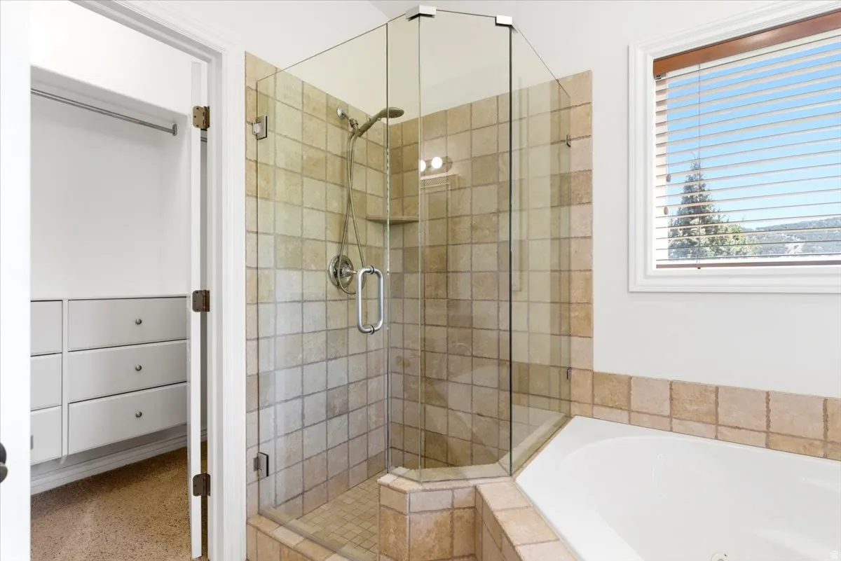 Walk-in shower with clear glass enclosure and square tile surround