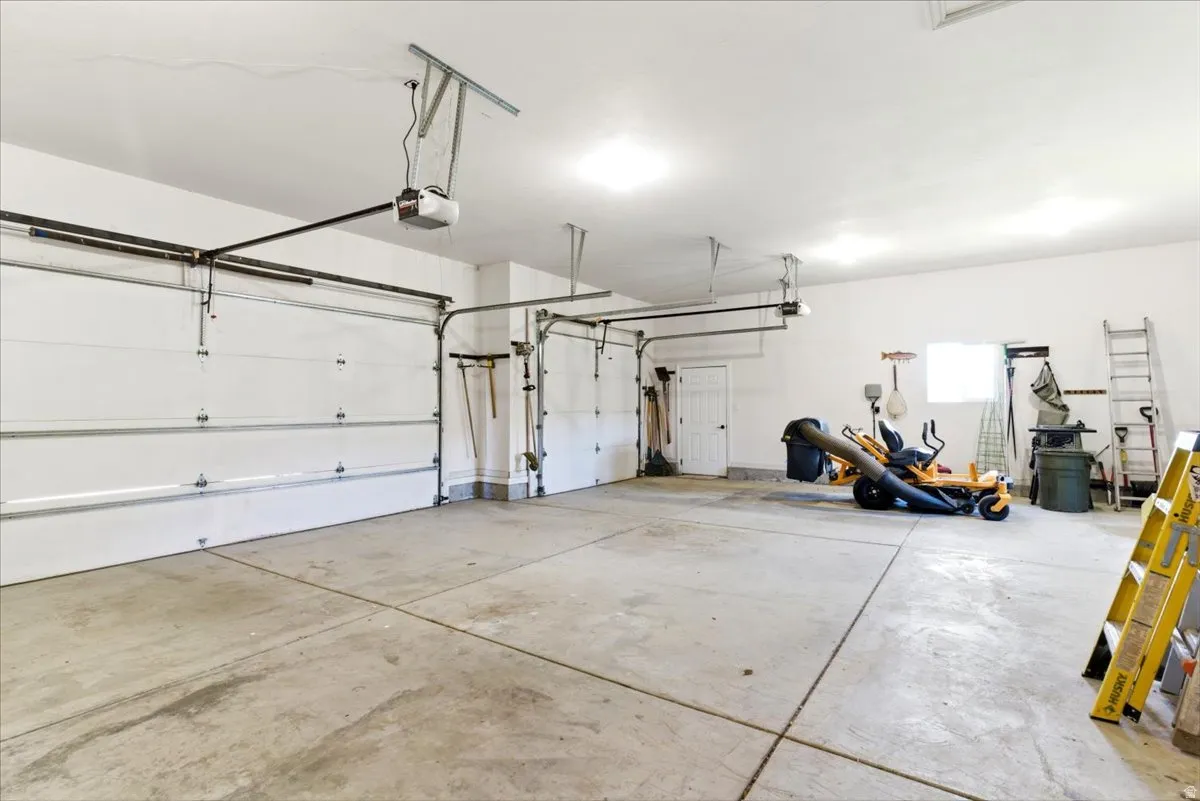 Spacious three-car garage featuring concrete flooring, multiple overhead garage door openers, and recessed lighting