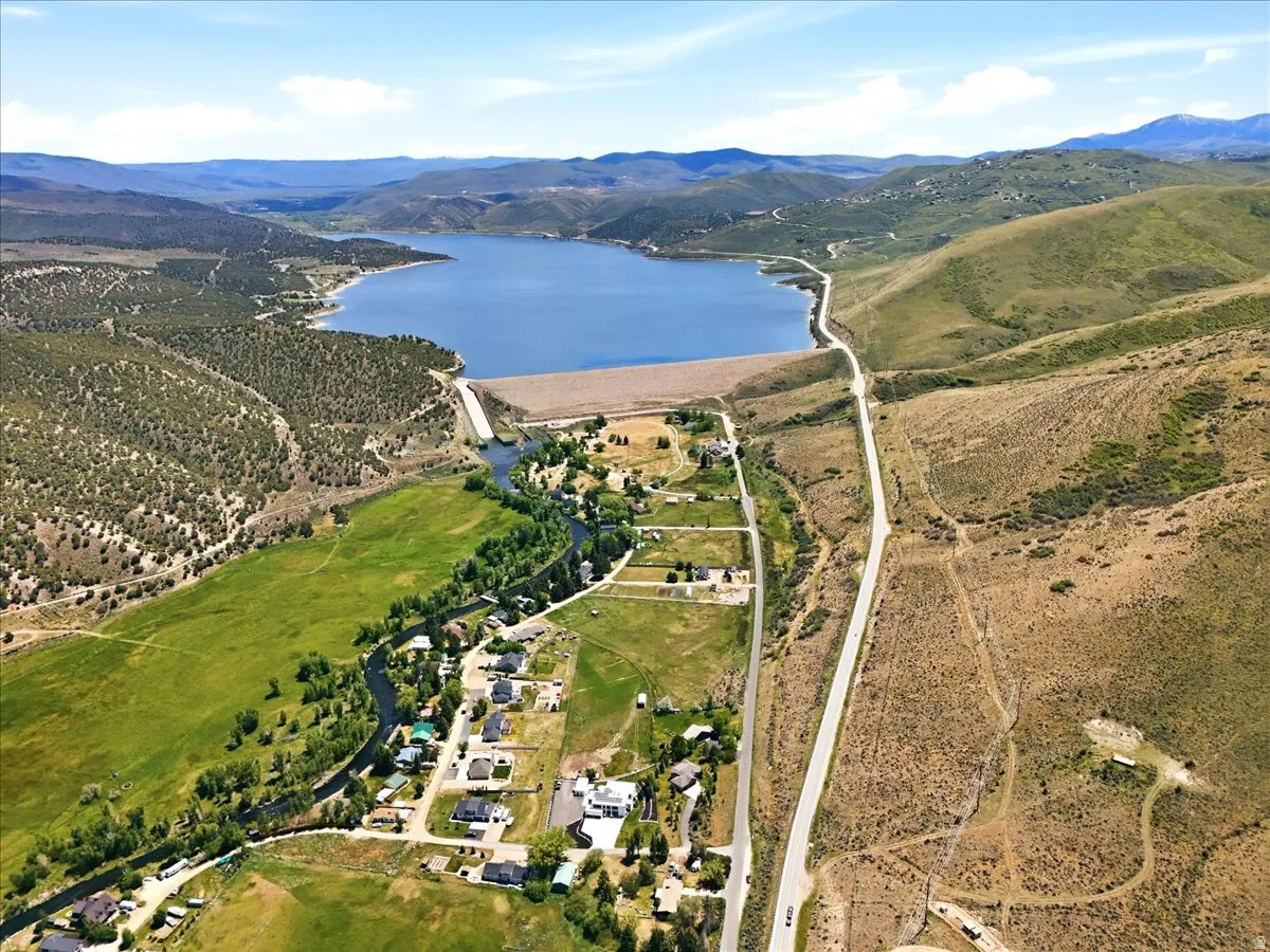 Expansive aerial vista featuring a prominent reservoir and dam, surrounded by rolling hills and scattered residential properties