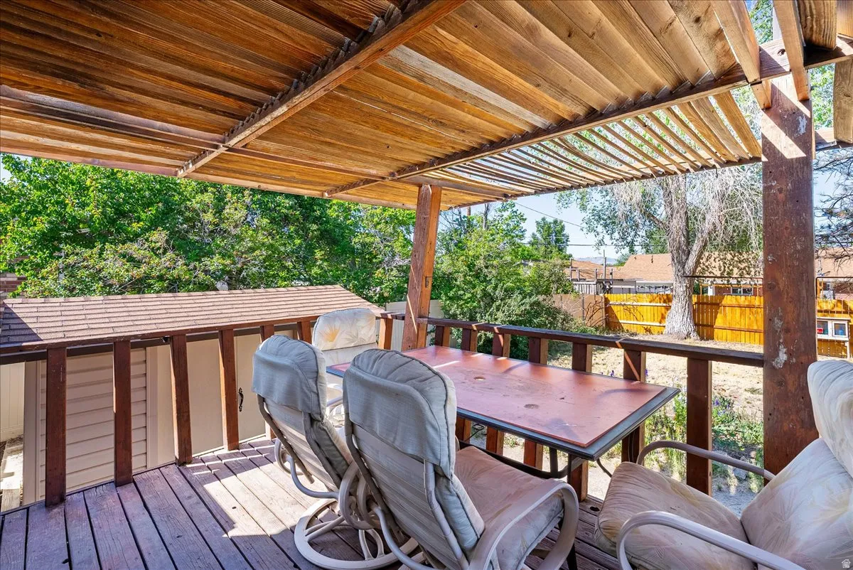 Expansive wood deck featuring a slatted wood pergola, wood railing, and a detached shed with a shingled roof