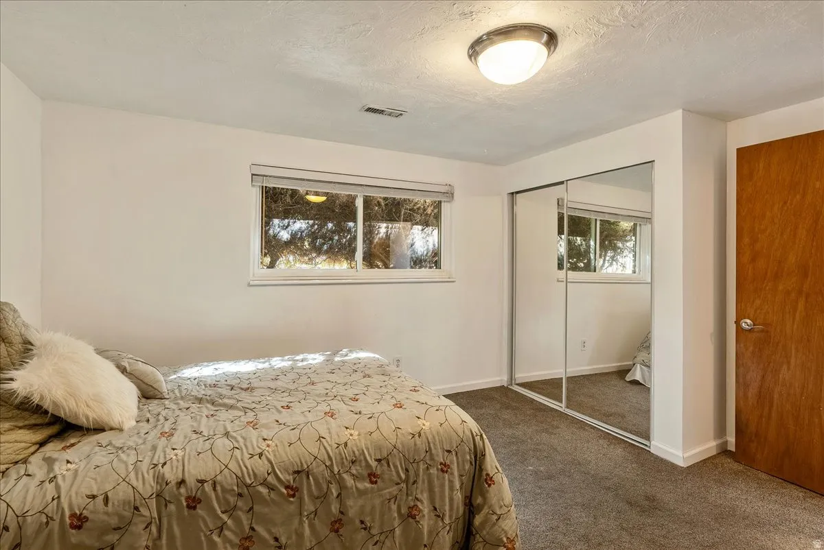 Bedroom featuring neutral wall paint, a double window with blinds, and mirrored sliding closet doors