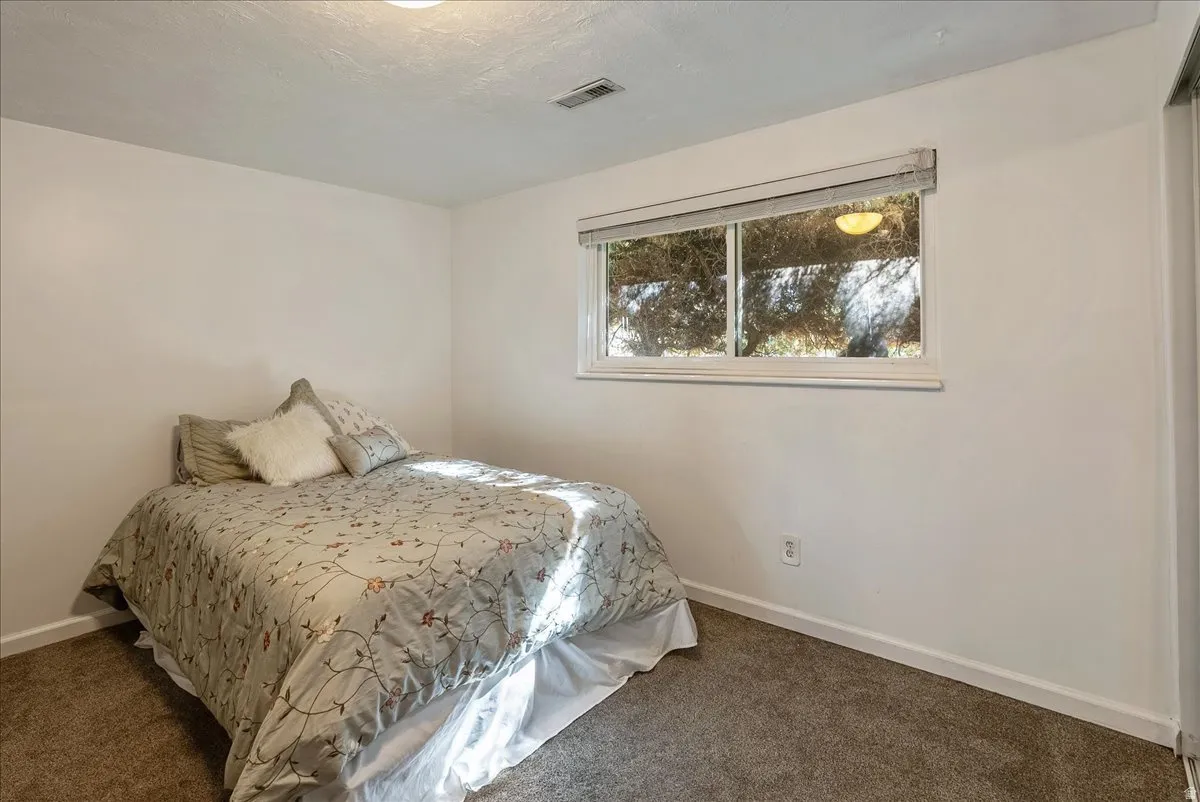 Bedroom featuring neutral wall paint, a double window with blinds, and textured ceiling