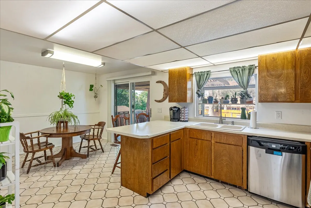 Kitchen featuring wood-finish cabinetry, light-toned countertops, and a dual basin sink
