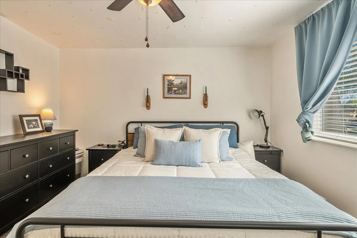 Bedroom featuring a ceiling fan, window with blinds, and white walls