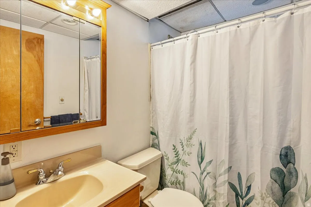 Bathroom featuring a vanity with a drop-in sink, a wall-mounted medicine cabinet with integrated lighting, and a white toilet