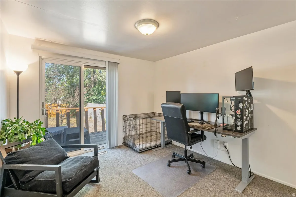 Carpeted room with a sliding glass door providing access to an exterior deck