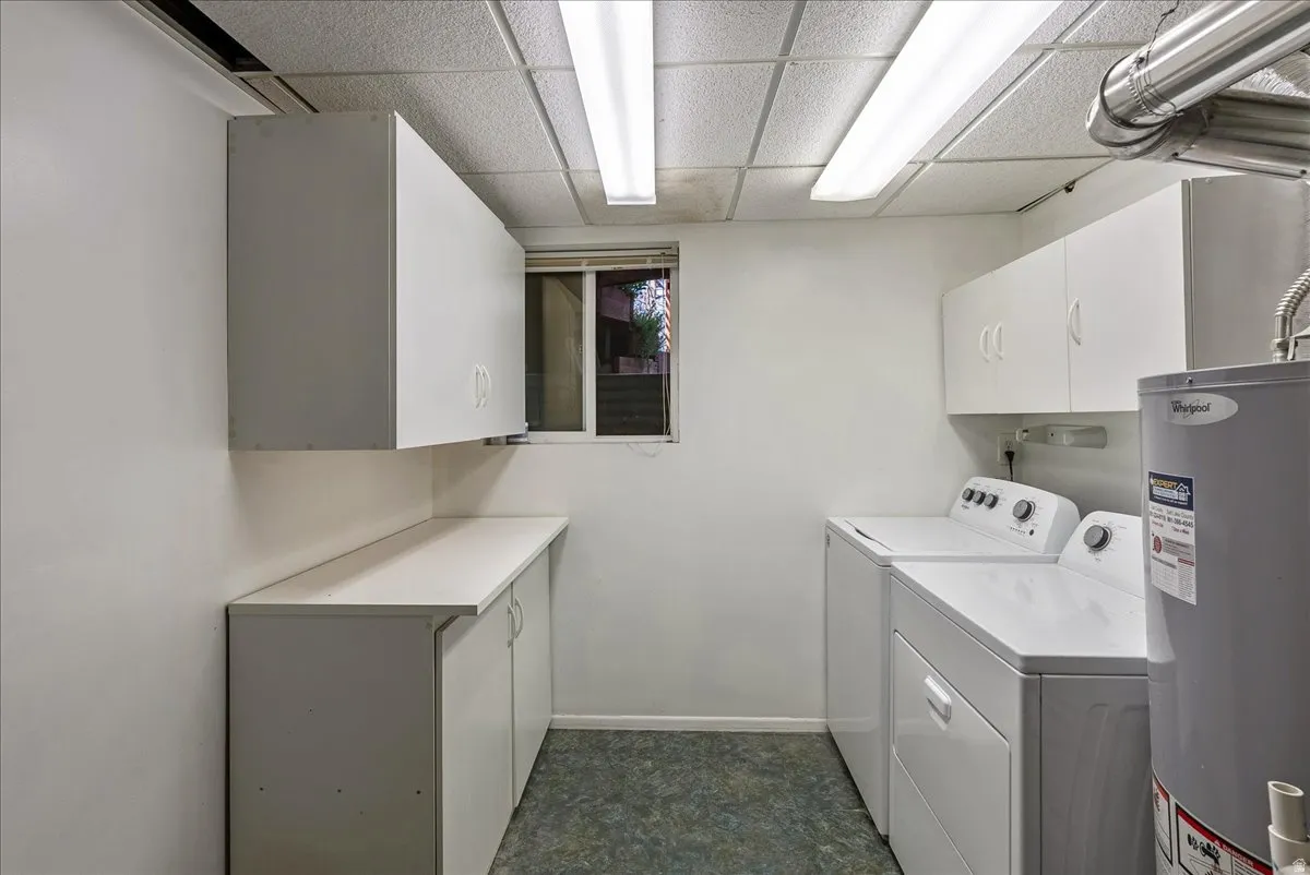Dedicated utility room featuring white cabinetry, a long countertop, and a window