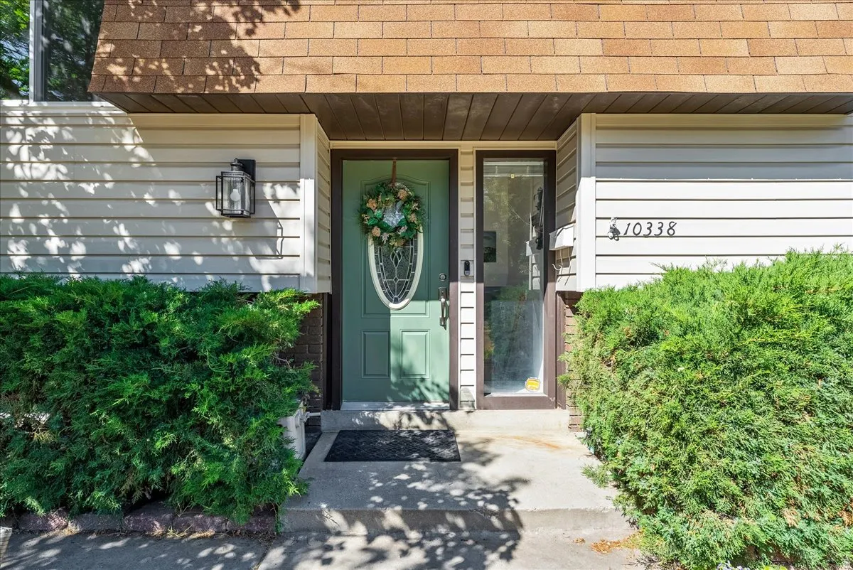 Entryway featuring a green door with oval glass insert, vertical sidelight, and a matte black wall lantern