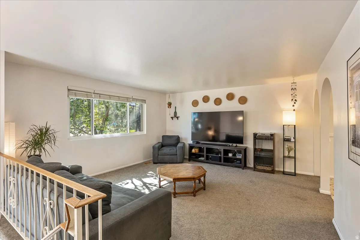Living area featuring large picture windows, light-toned carpeting, and white walls